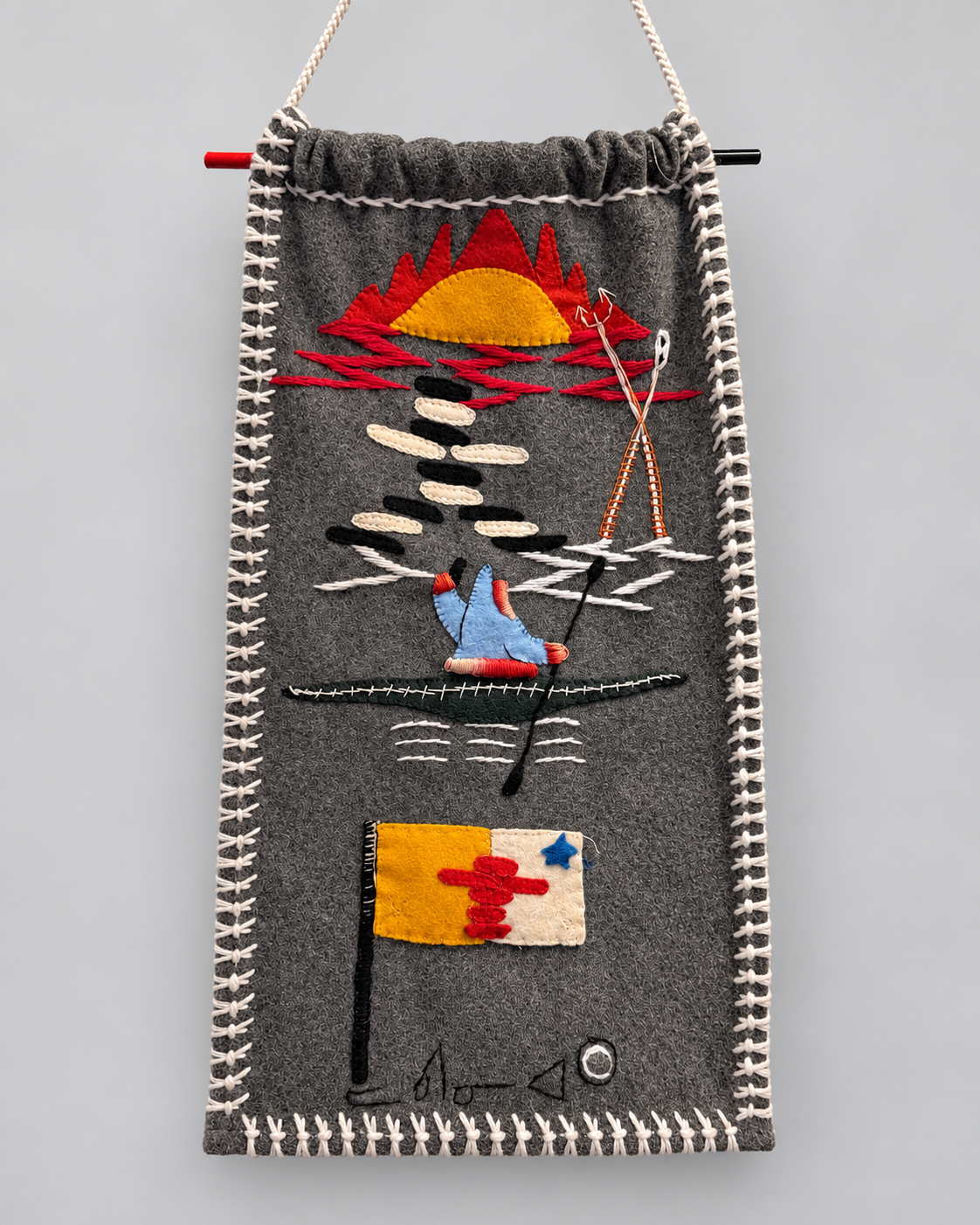 Stitched textile artwork showing a sunset and a kayaker